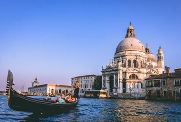 Un gondoliere con turisti in un canale di Venezia con il Palazzo Ducale sullo sfondo