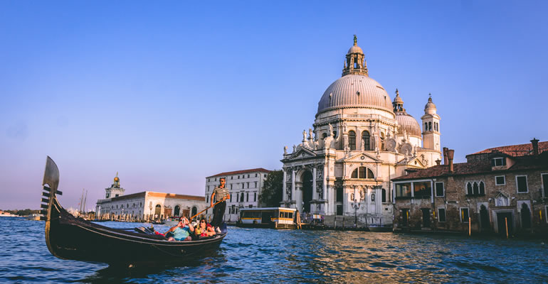Un gondoliere con turisti in un canale di Venezia con il Palazzo Ducale sullo sfondo